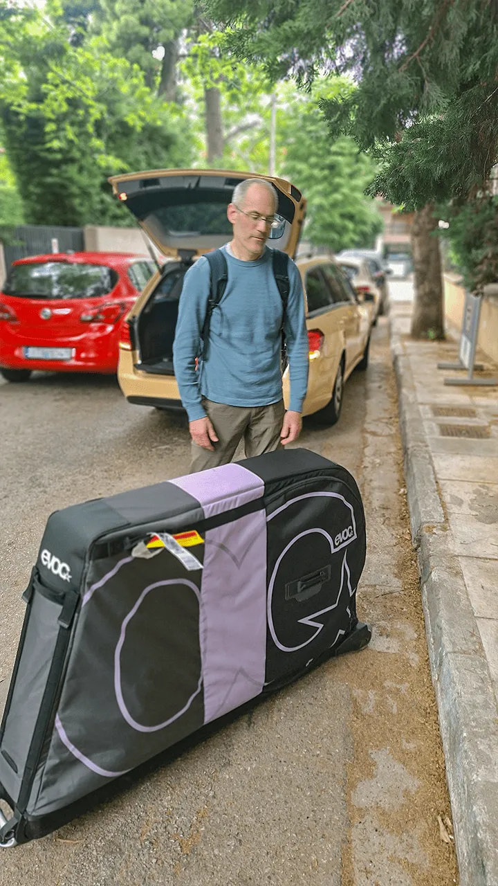 A client unloading a padded EVOC bike travel bag from the Mercedes station wagon in Athens
